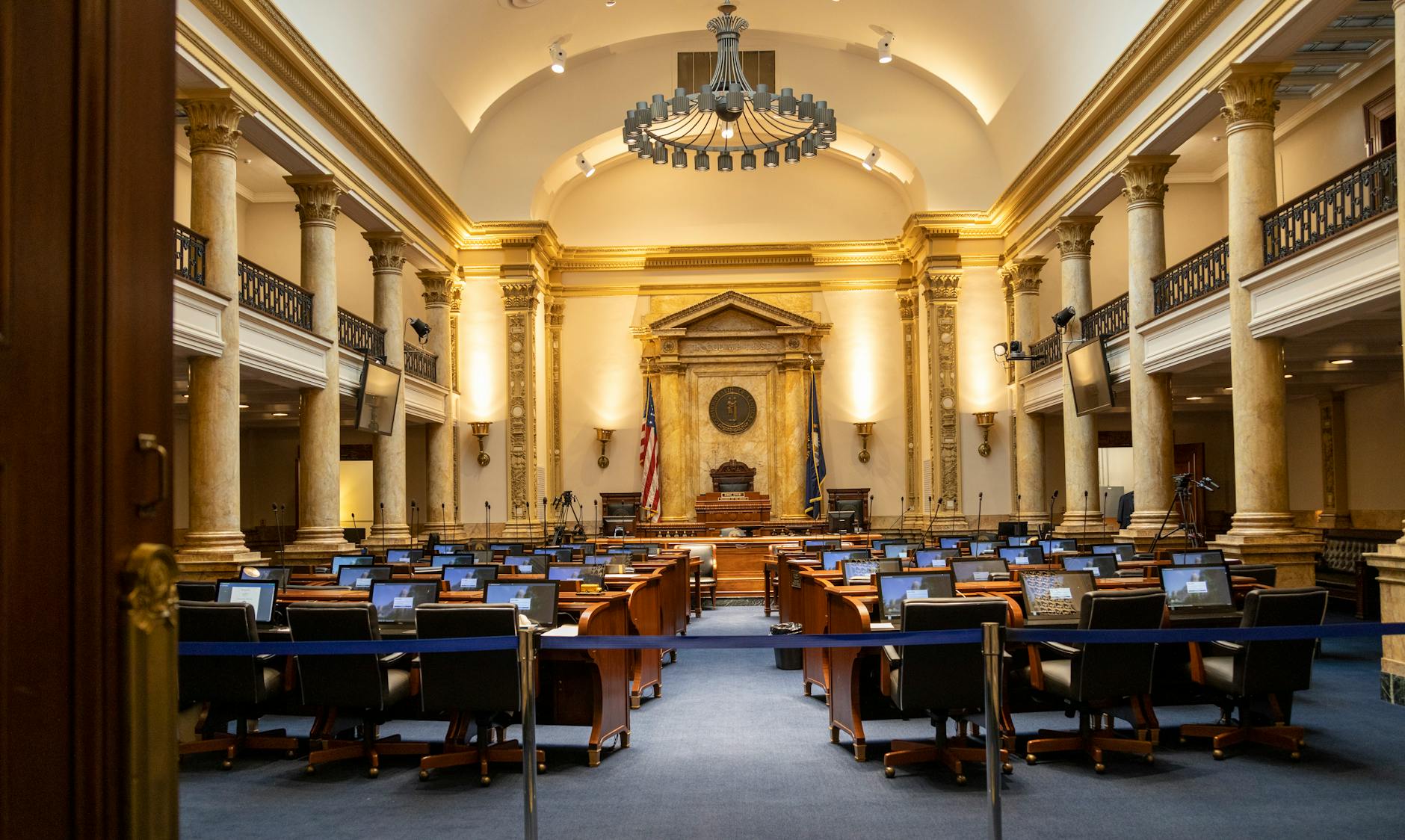 A grand government chamber with columns and seating, representing state legislative and legal proceedings car.